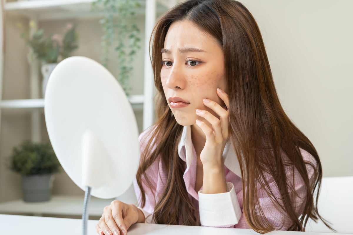 Asian woman assesses her face for sun damage