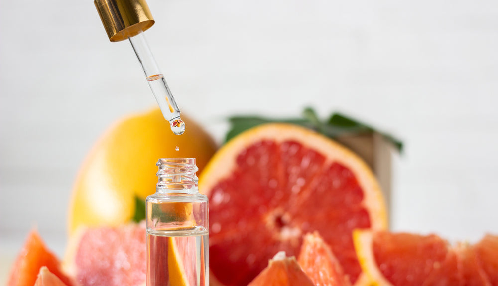 Grapefruit extract behind a bottle of skincare serum