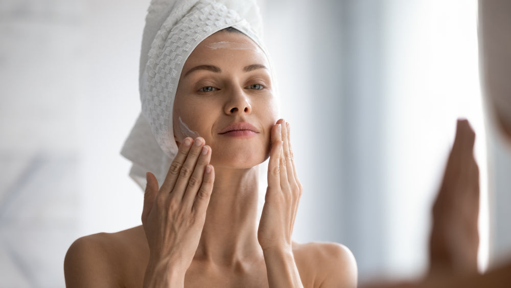 woman applying sunscreen and moisturizer to face