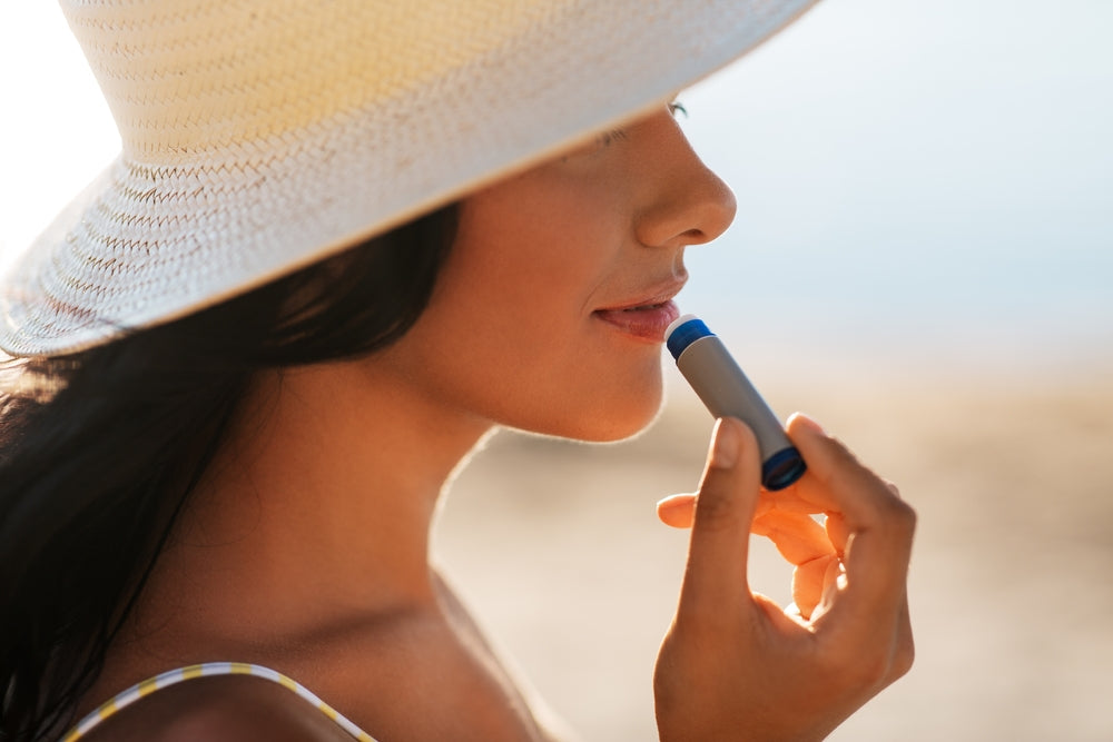 Woman applying lip balm in the sun