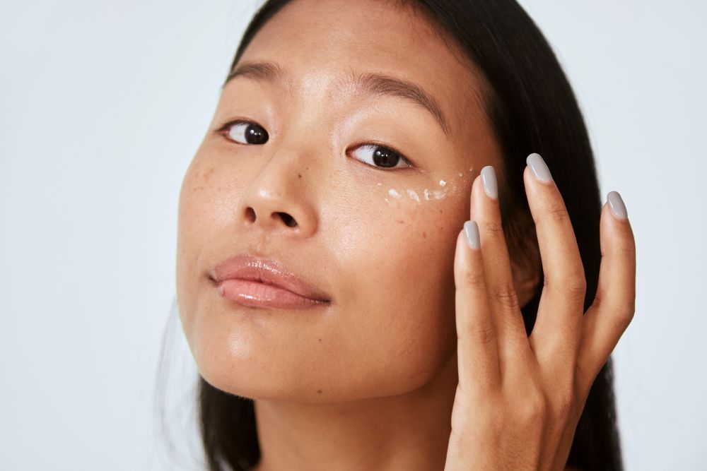 A woman applying eye cream under her eyes