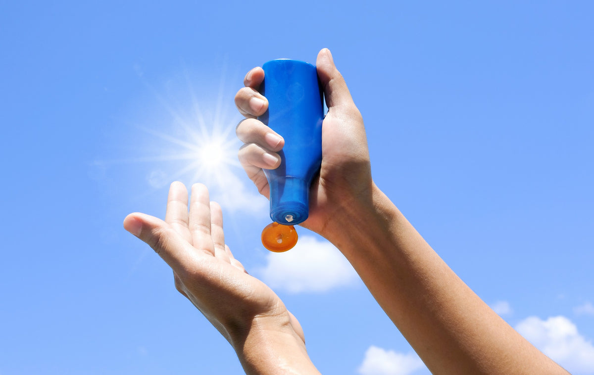 hands applying sunscreen from a bottle