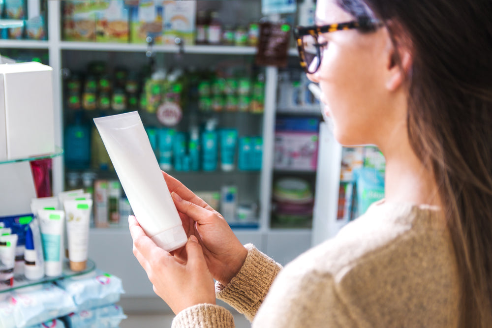 Woman examining ingredients and expiration date on sunblock product