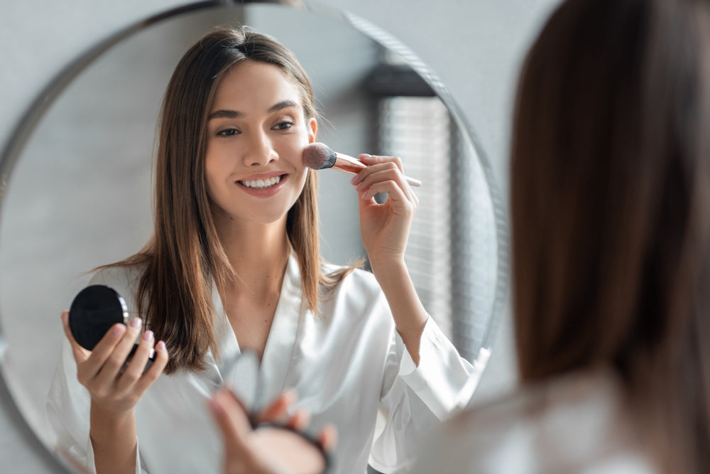 Woman looking in mirror applying sunscreen with SPF over makeup
