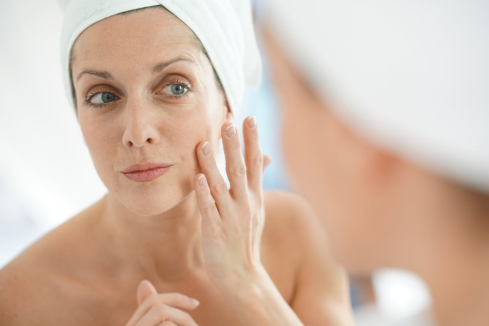 Woman looking at face and applying makeup on skin