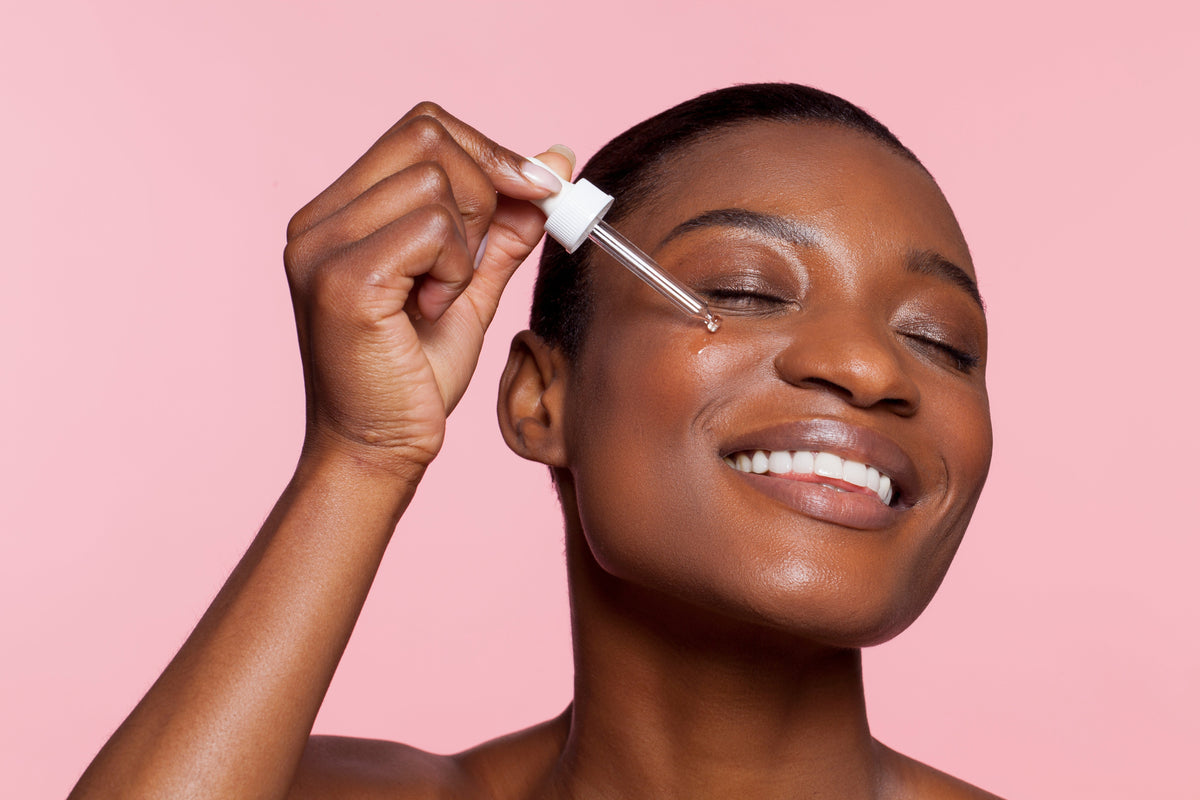 Black woman applying green tea leaf extract to face 