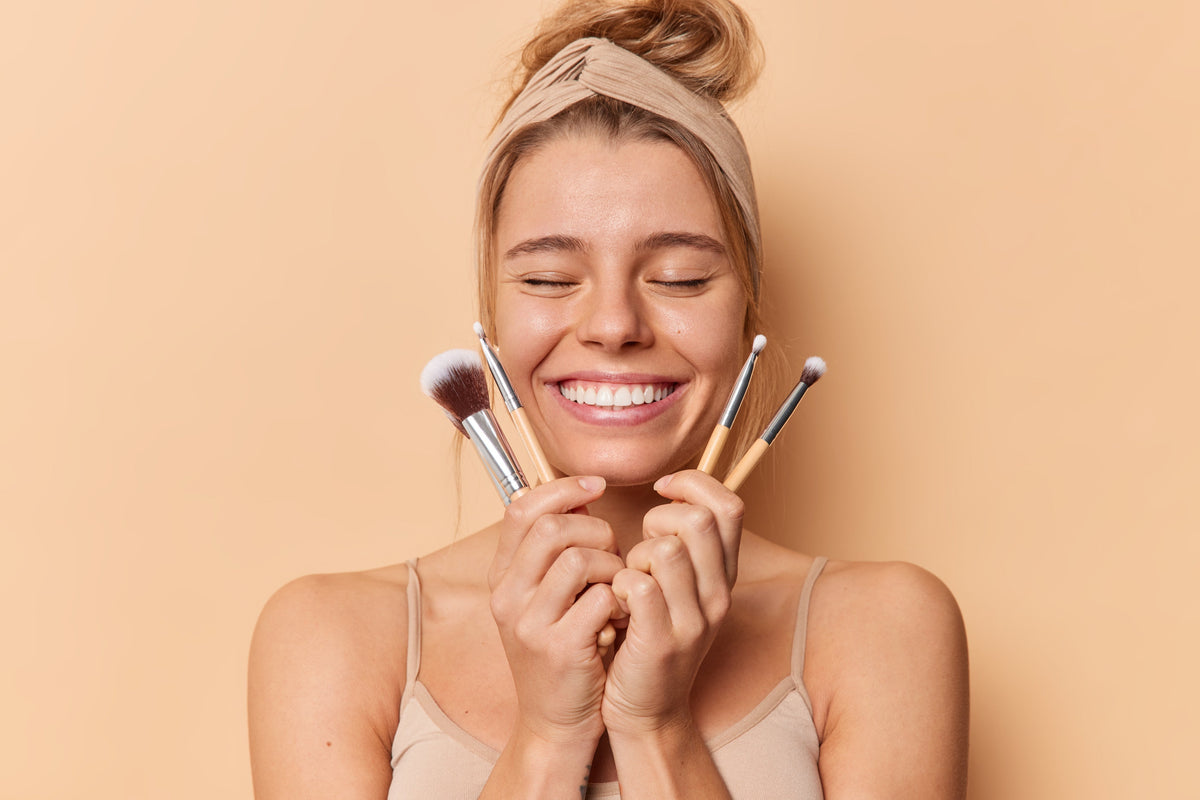 Woman holding makeup brushes while smiling 
