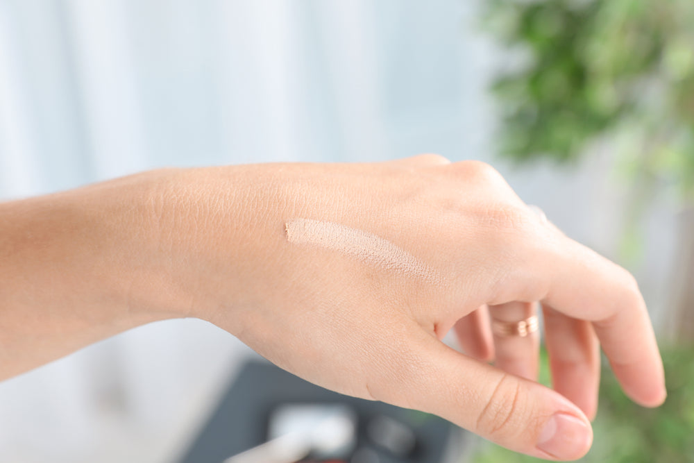 Close-up of a woman’s hand with a swatch of liquid makeup.