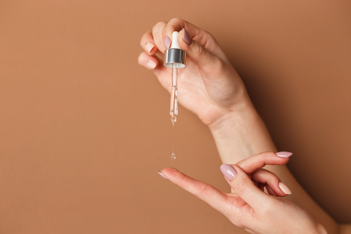 Woman dropping skincare serum onto her finger