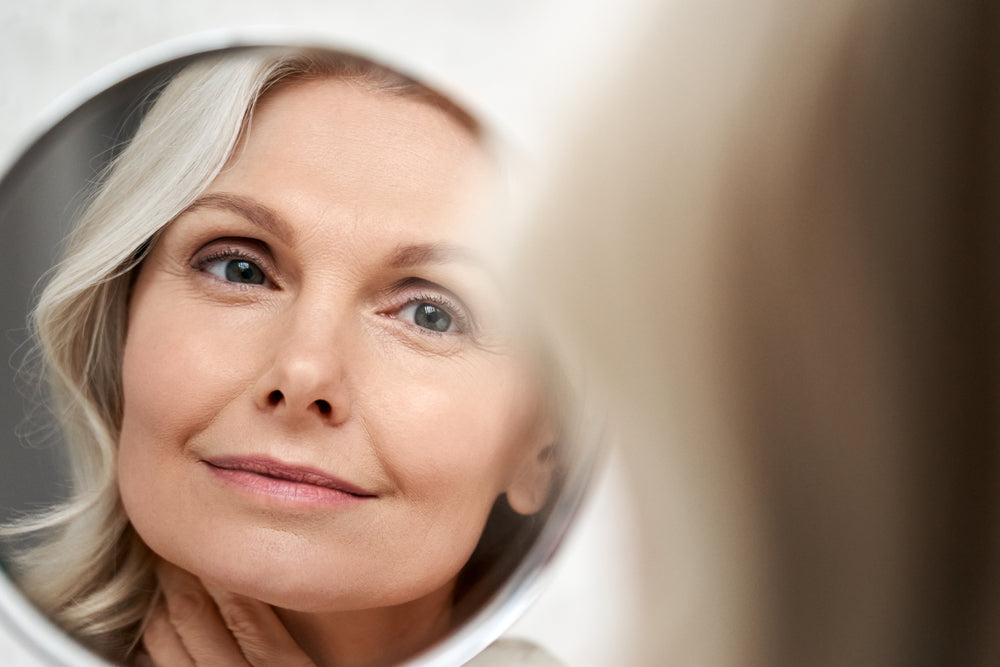 Mature woman looking at the skin on her face in the mirror