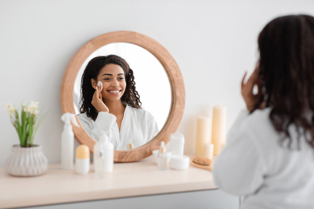 Young Black woman doing skincare in front of a vanity.