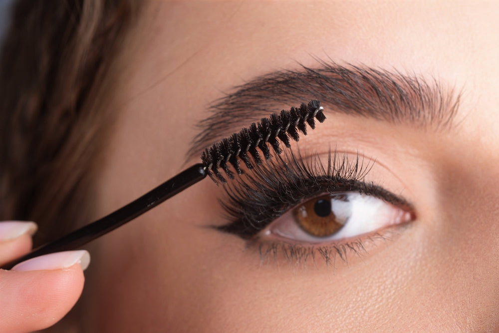 Close-up of woman brushing through her long lashes.