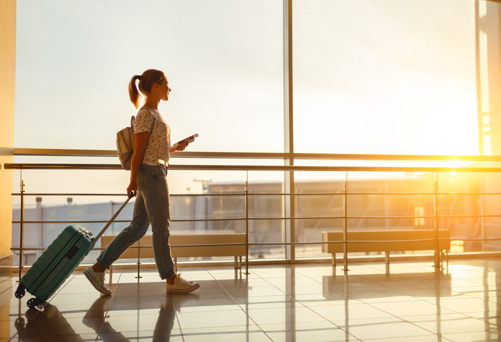 Woman walking through airport with suitcase.