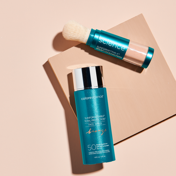 Total Protection Face Shield Bronze SPF 50 and Sunforgettable® Total Protection® Brush-On Shield laying flat on beige background | all
