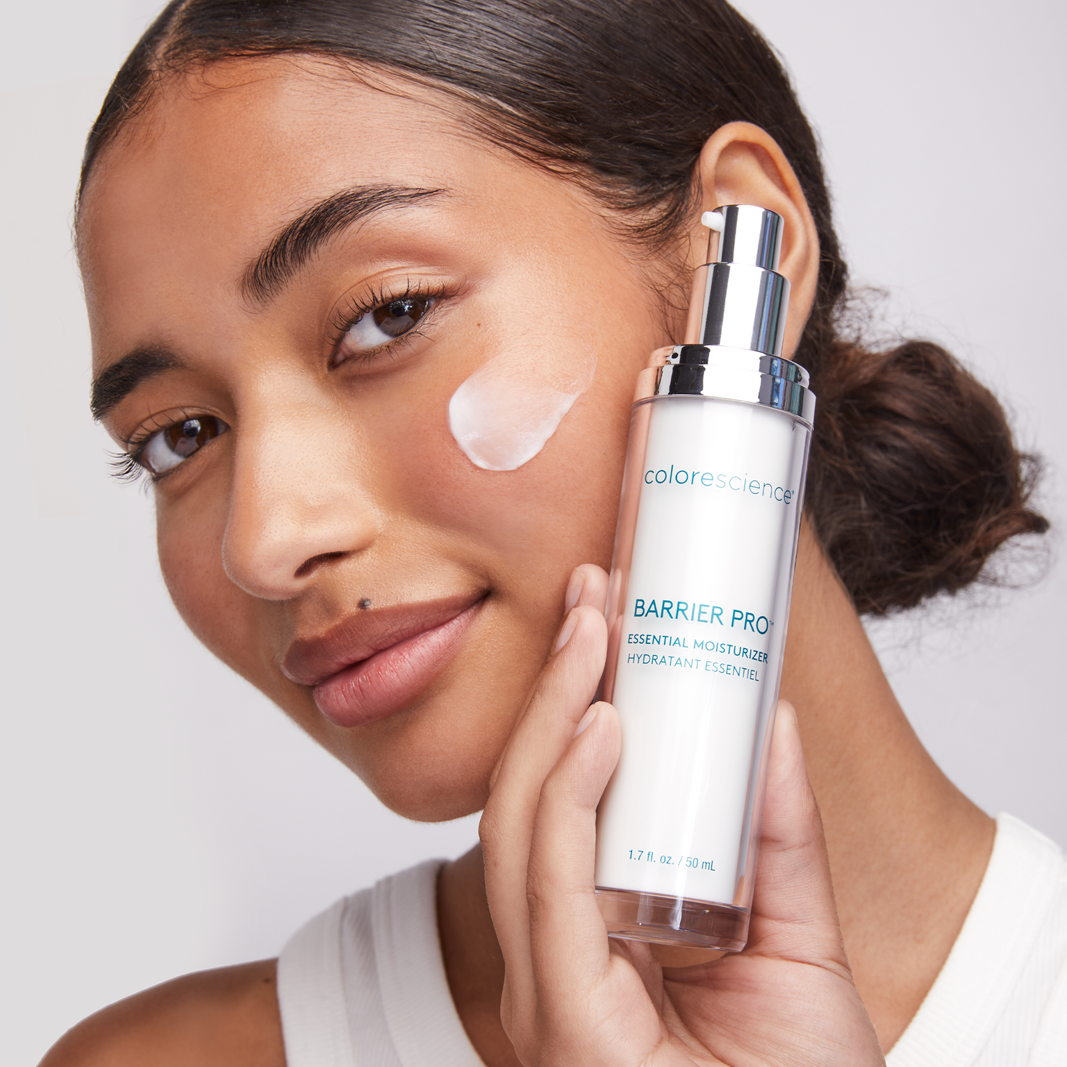 woman holding Barrier Pro™ Essential Moisturizer with a swatch on her cheek || all