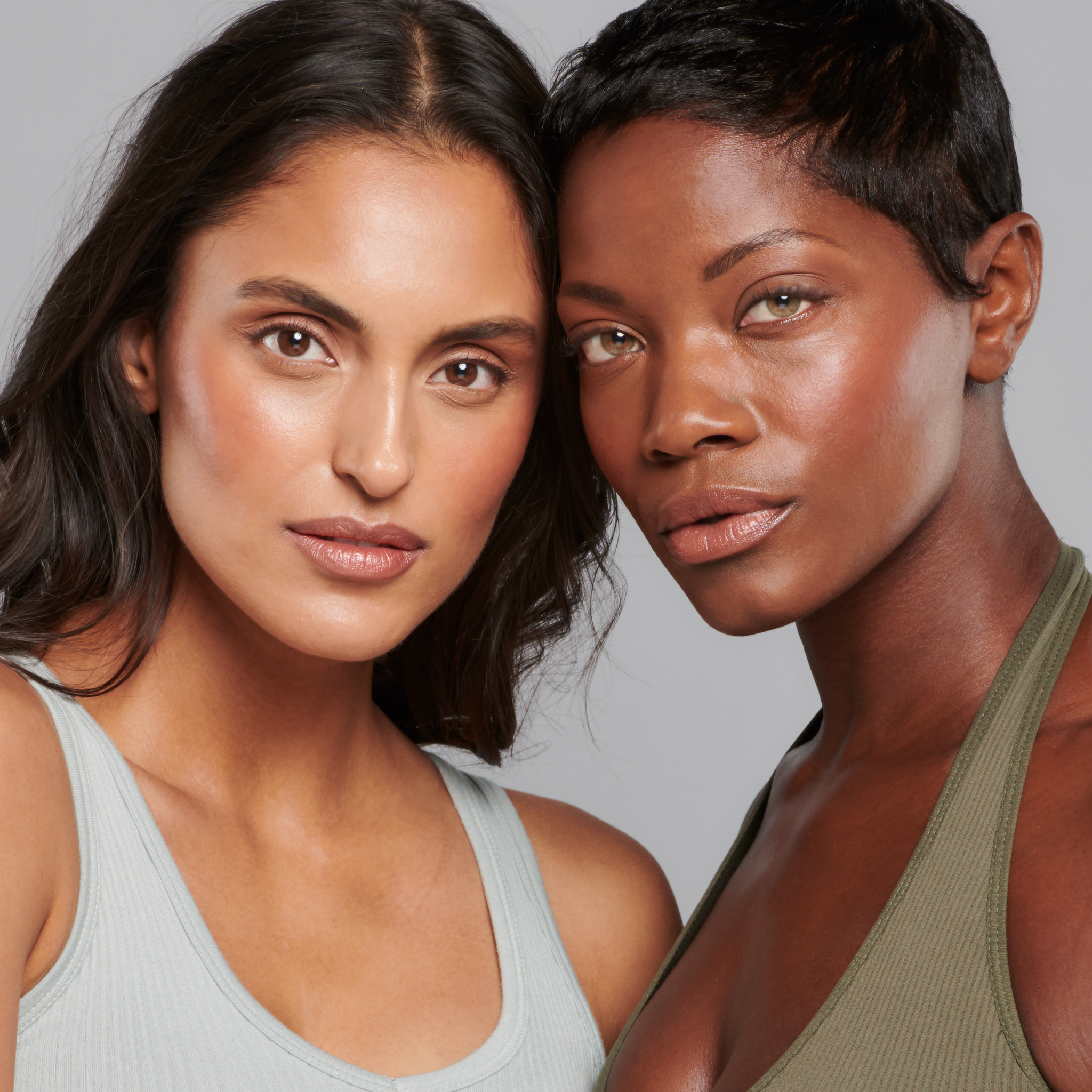 Two models wearing Sunforgettable® Total Protection™ Face Shield Glow SPF 50 in Medium and Deep || all